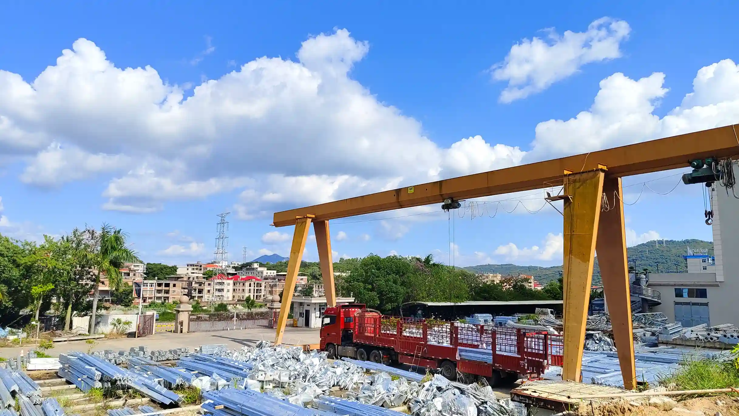 Minyi Gantry crane and red truck at industrial yard with city backdrop​