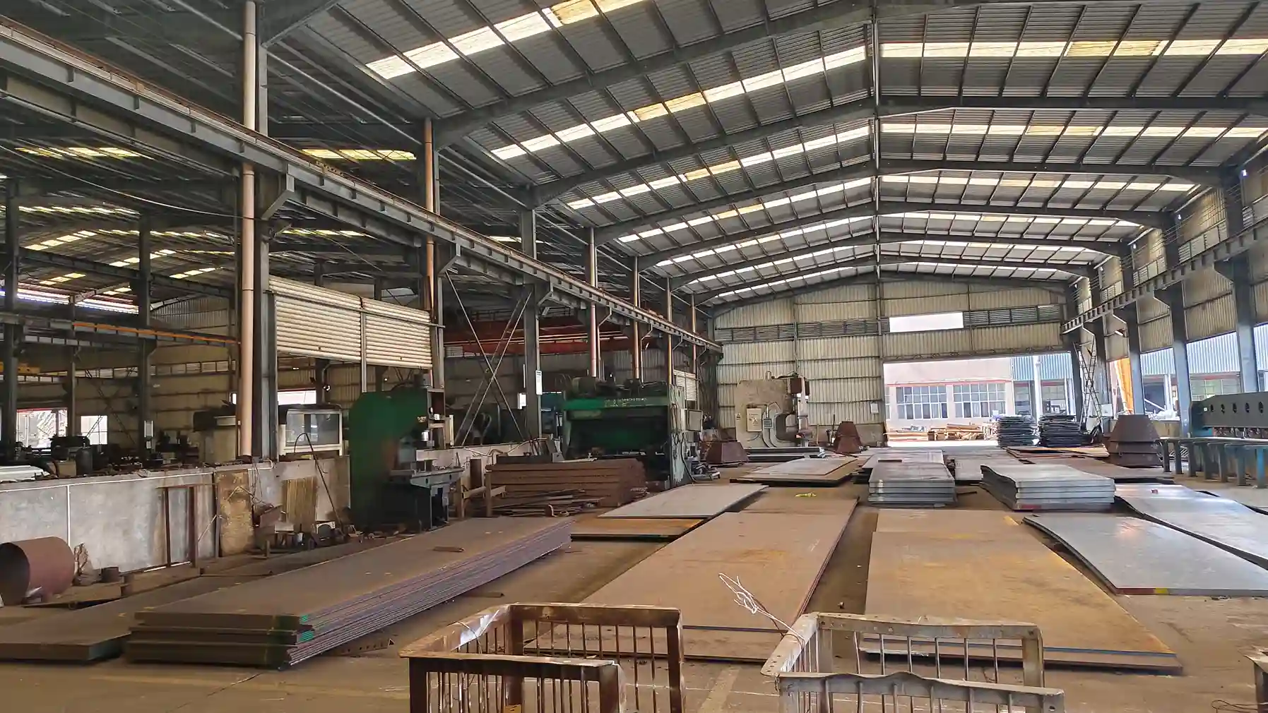 Industrial warehouse with stacked steel plates and overhead cranes