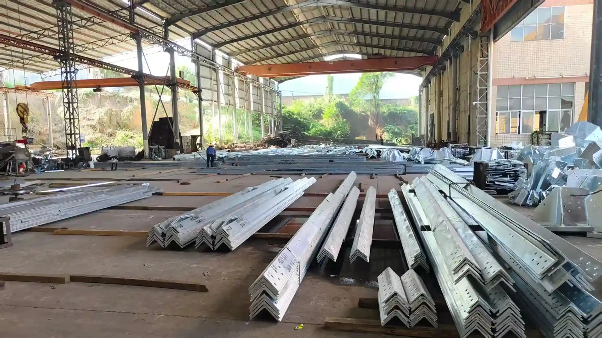 Warehouse interior with stacked steel beams and orange crane