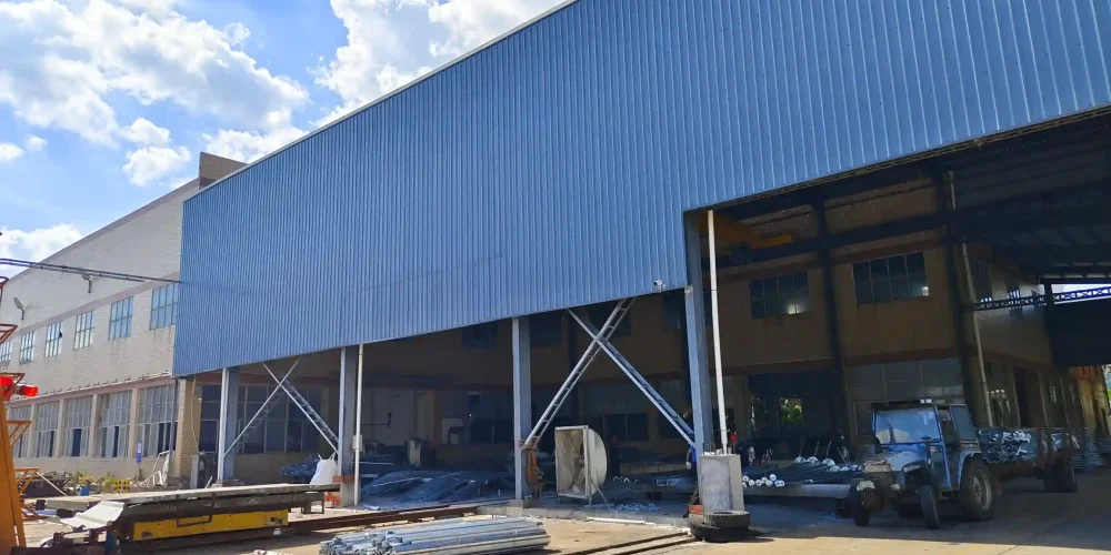 ​Industrial yard with metal pipes, blue forklift, and factory building​